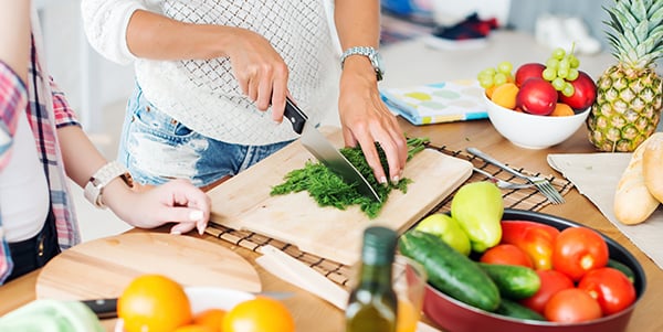 Woman chopping up herbs with fresh fruit and vegetables around her